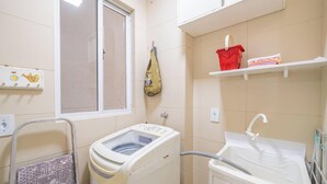 Un espace buanderie comprenant un lave-linge, un évier et une fenêtre.