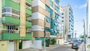 Un immeuble à plusieurs étages doté de balcons, d’une enseigne de restaurant bien visible et offrant une vue dégagée sur la rue et les voitures garées.