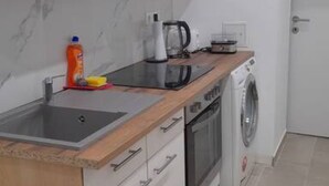 A kitchen with a sink, a coffee maker, a kettle, a microwave, and a washing machine.