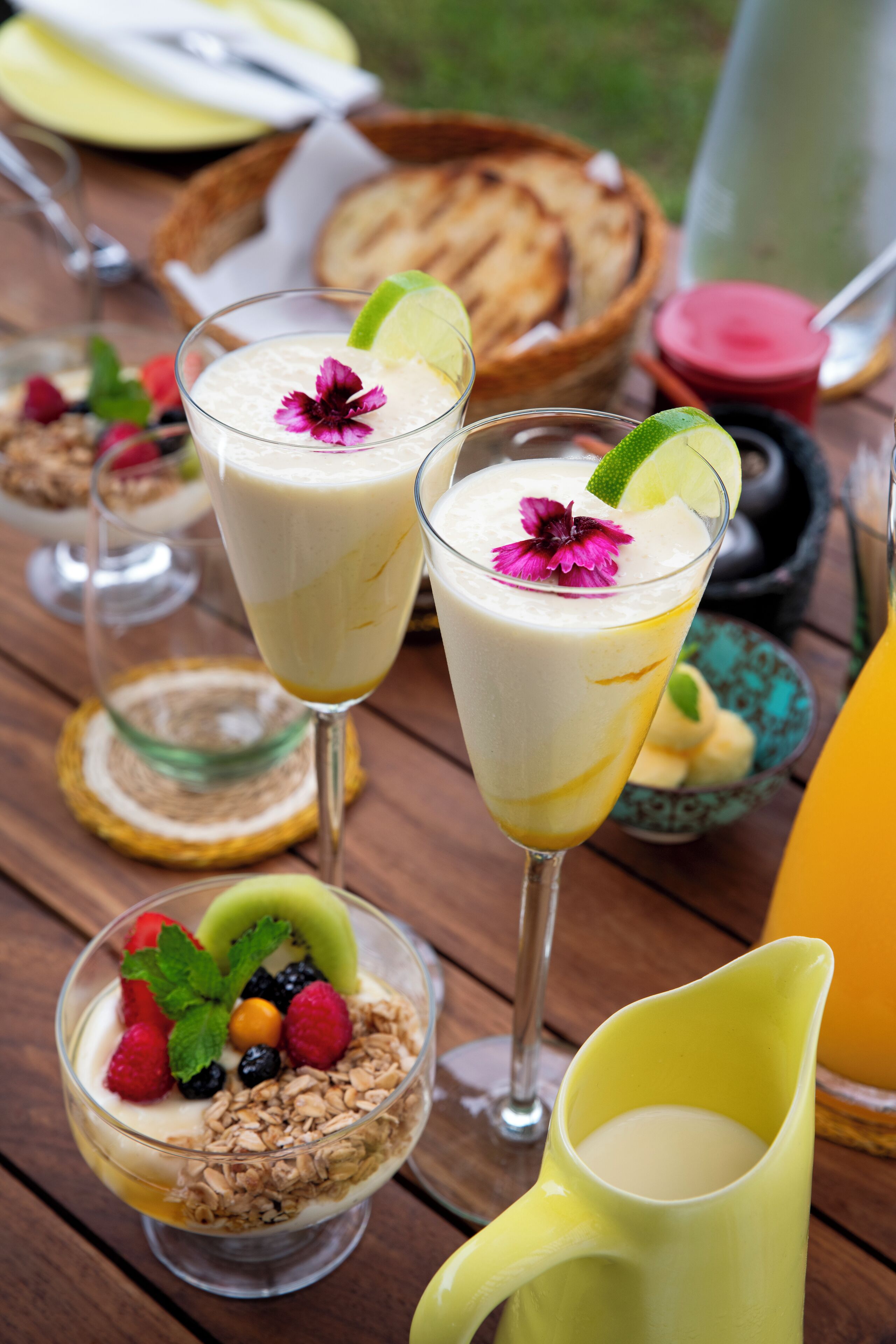 A table with various food items including a glass of yogurt with fruit and a bowl of granola with berries.
