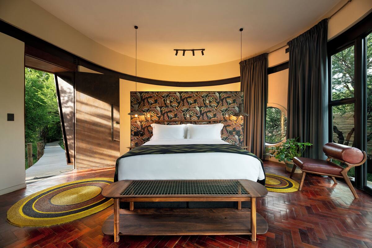 Un dormitorio moderno con una cama grande, una cabecera original, un banco y vistas al exterior.