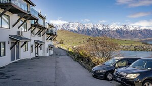 A modern building with balconies overlooking a mountainous landscape and a lake. - Outlook Oasis, Uninterrupted Lake Views (Queenstown)