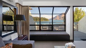 Habitación de hotel moderna con un amplio ventanal que ofrece una vista panorámica de montañas y un lago.