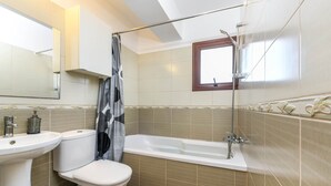 A bathroom with a toilet, sink, bathtub, and shower. - Nissi Apartment 102 (Ayia Napa)