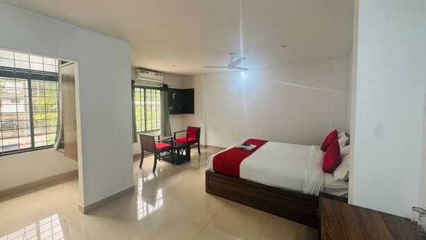 Habitación de hotel con cama, escritorio con dos sillas, televisor y ventilador de techo.