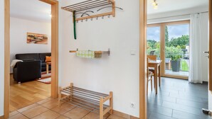 Ein modernes Wohnzimmer mit einem schwarzen Sofa, einer Holzbank, einem Wäscheständer und einem Gemälde an der Wand.