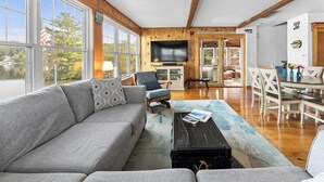 A living room with a sofa, armchair, coffee table, and a TV. - Waterfront Retreat | Dock, Kayak & Lake Views (Hopkinton)