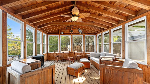 A wooden deck with seating, a ceiling fan, and large windows. - Waterfront Retreat | Dock, Kayak & Lake Views (Hopkinton)