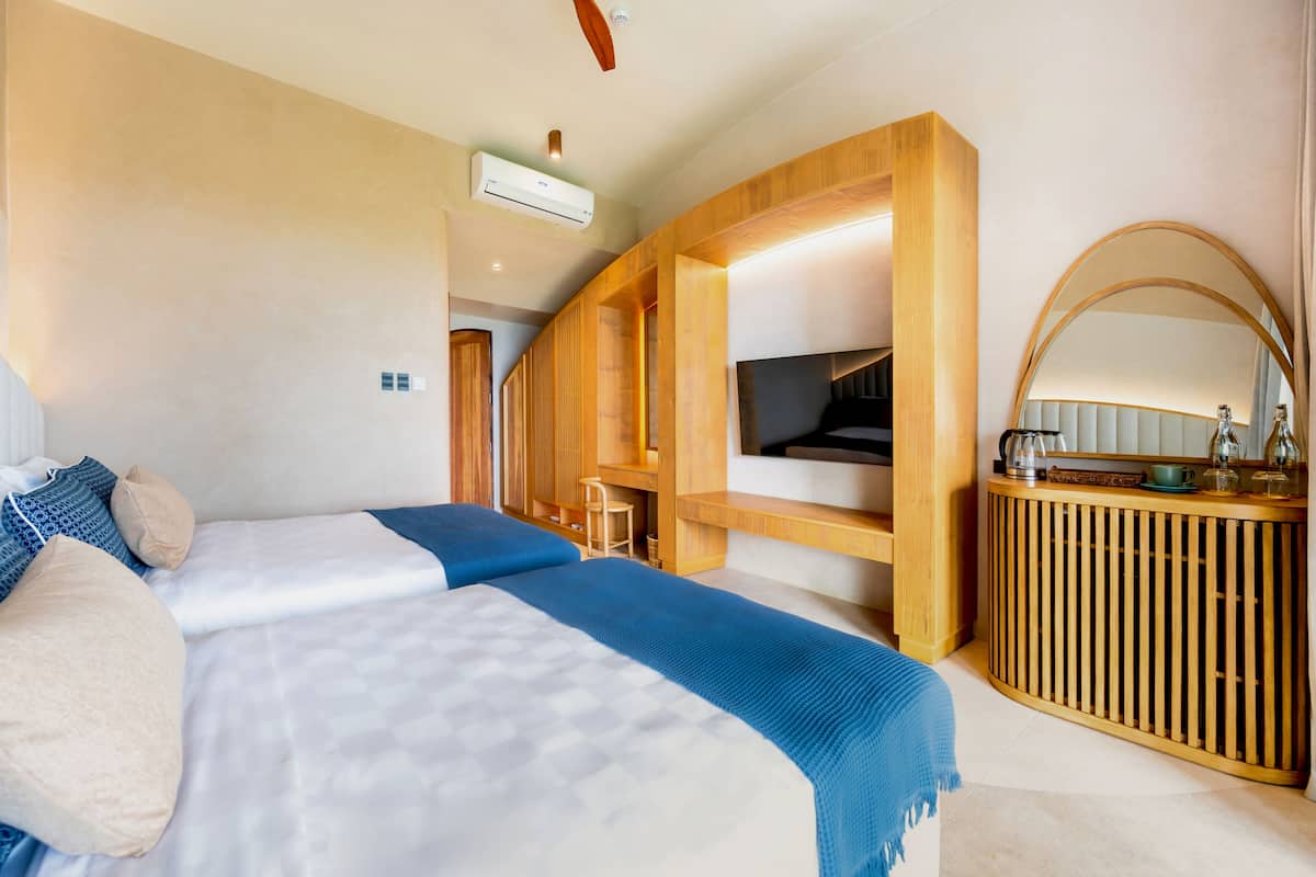 Habitació d'hotel amb un llit, escriptori, televisió i mirall.