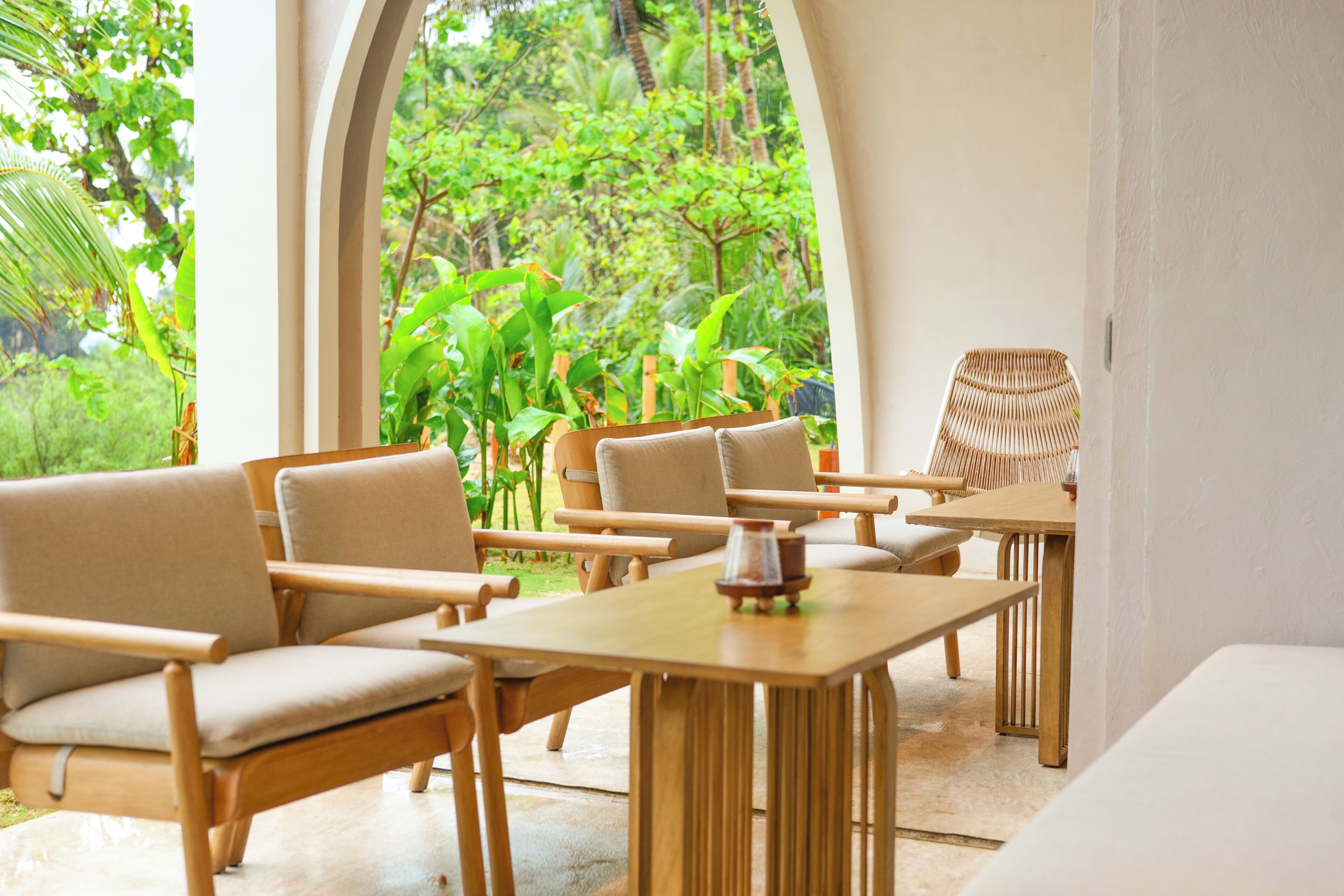 A modern outdoor seating area with wooden furniture and a view of lush greenery.