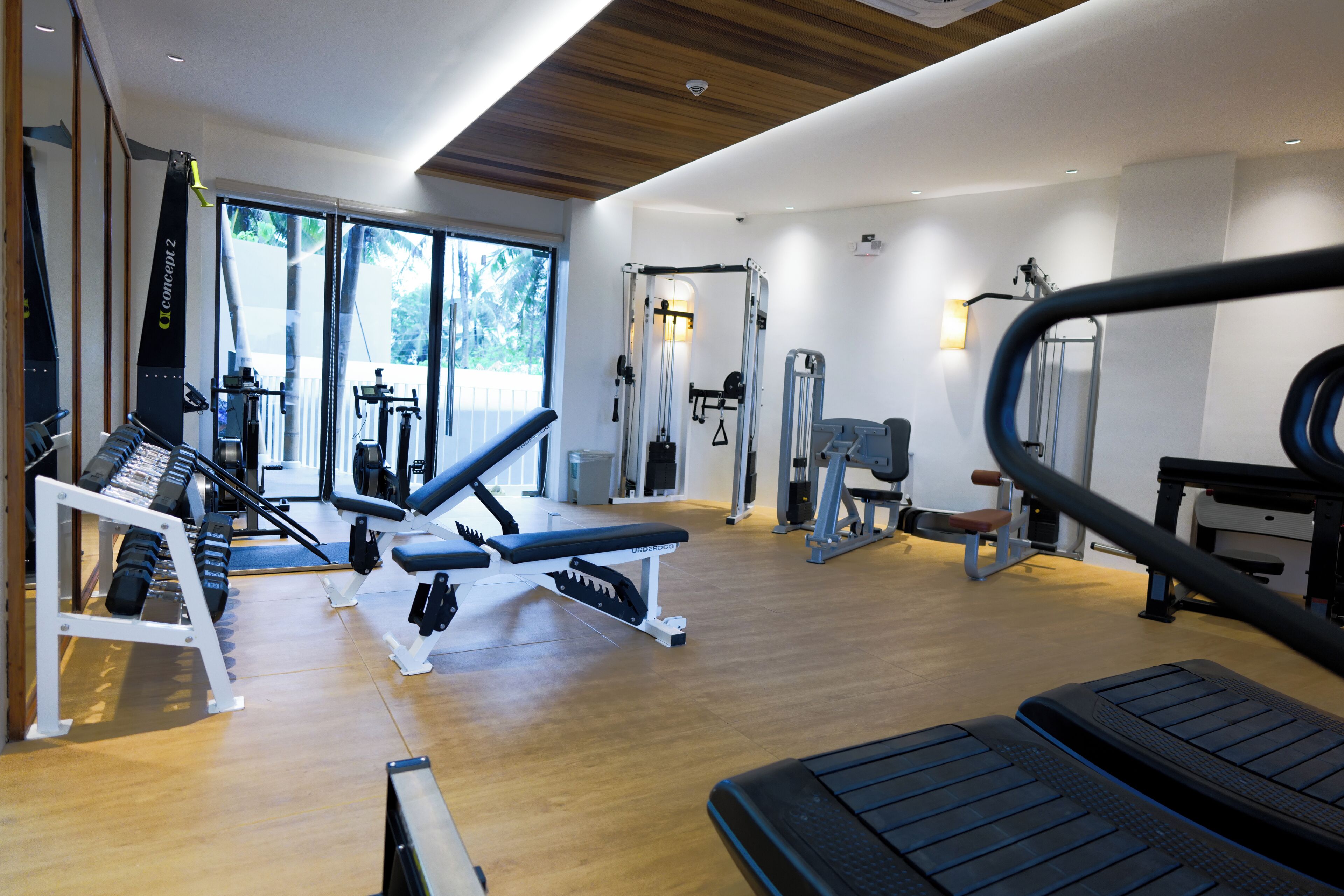 Un gimnasio con equipo cardiovascular, máquinas de pesas y pesas sueltas.