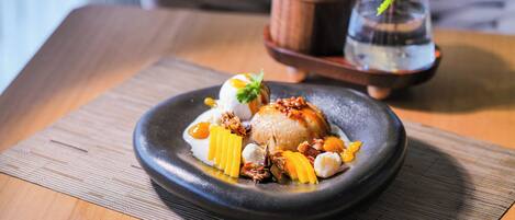 A dessert on a black plate with a wooden table and a small potted plant in the background.