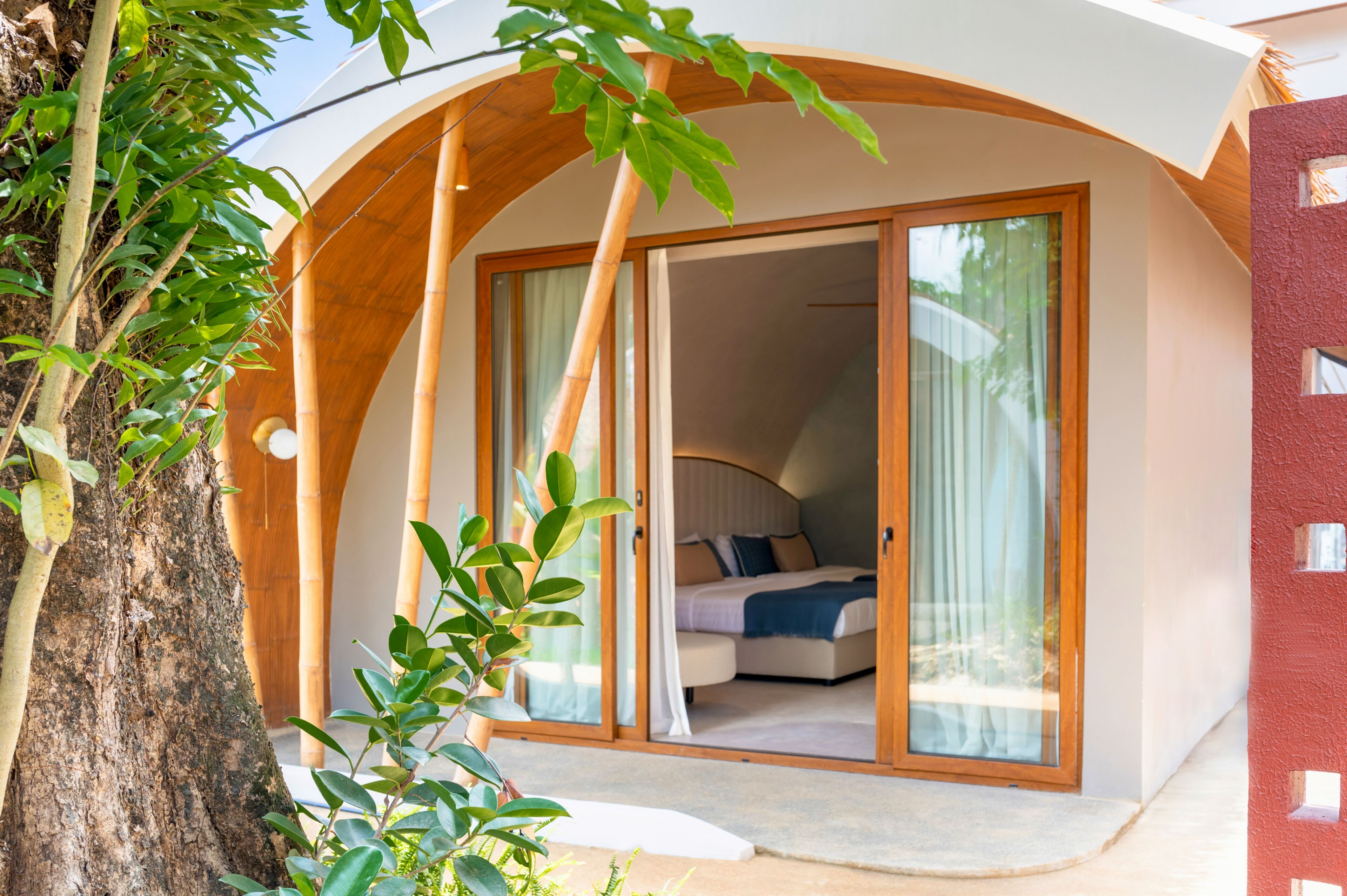 A modern room with a curved wooden arch, a bed with white bedding, and a large sliding glass door leading to a balcony.