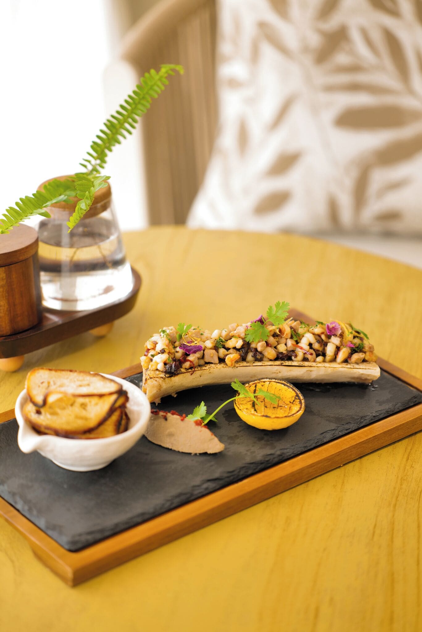 A meal with a baked dish, bread, and a small bowl on a wooden table.