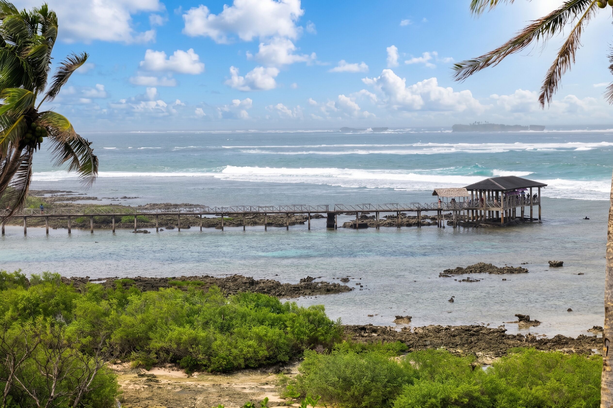 A coastal scene with a pier extending into the water, a covered structure on the pier, and lush greenery in the foreground.