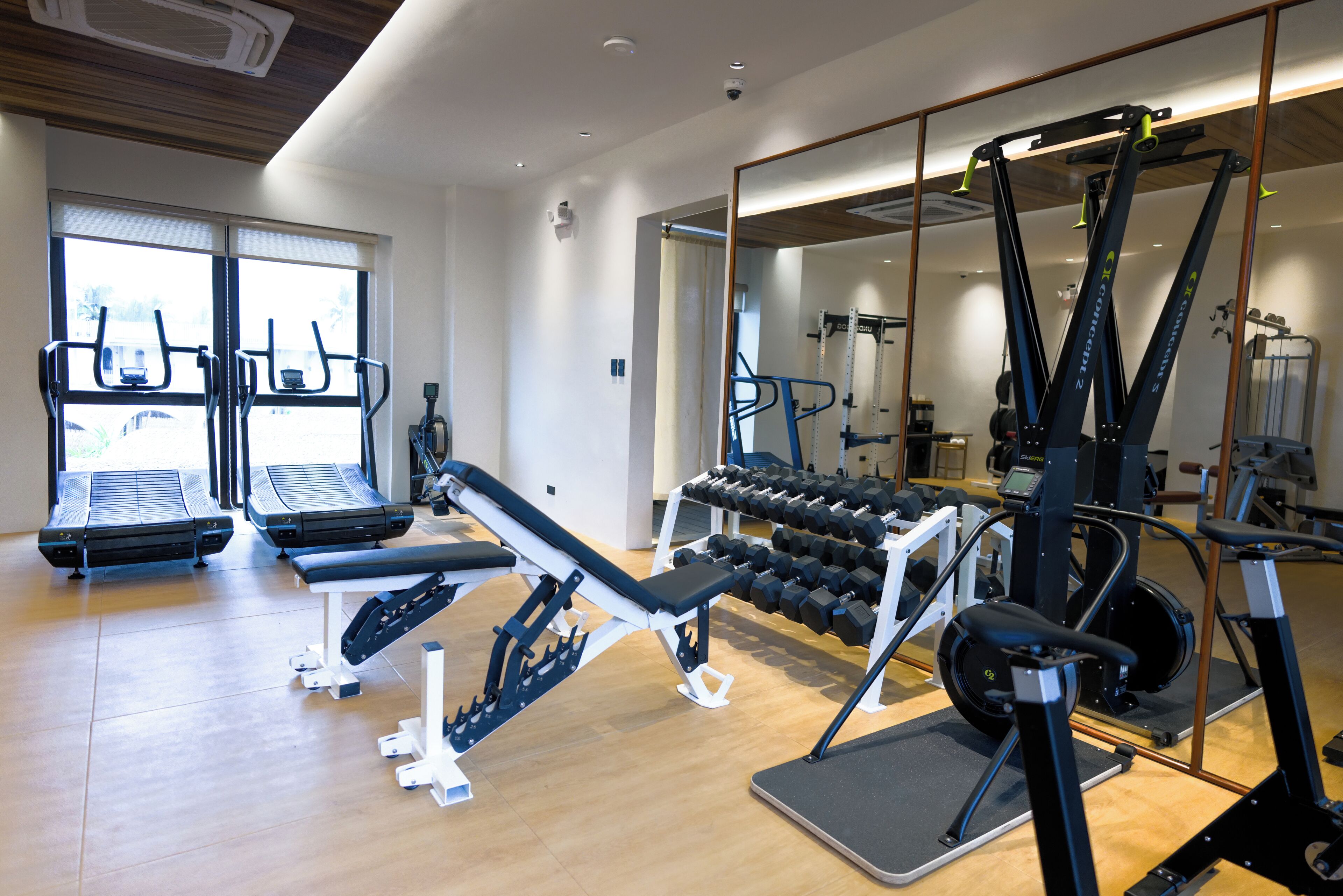 A gym with treadmills, weight machines, and dumbbells.