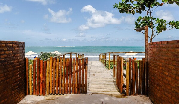A wooden pathway leading to a beach with a view of the ocean.