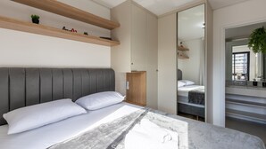 Un dormitorio moderno con cama, estanterías empotradas, armario y espejo.