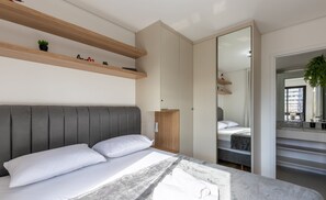 A modern bedroom with a bed, built-in shelves, a wardrobe, and a mirror. - Apto cond c/ acad. 400m Mercado Municipal NFE1544 (Curitiba)