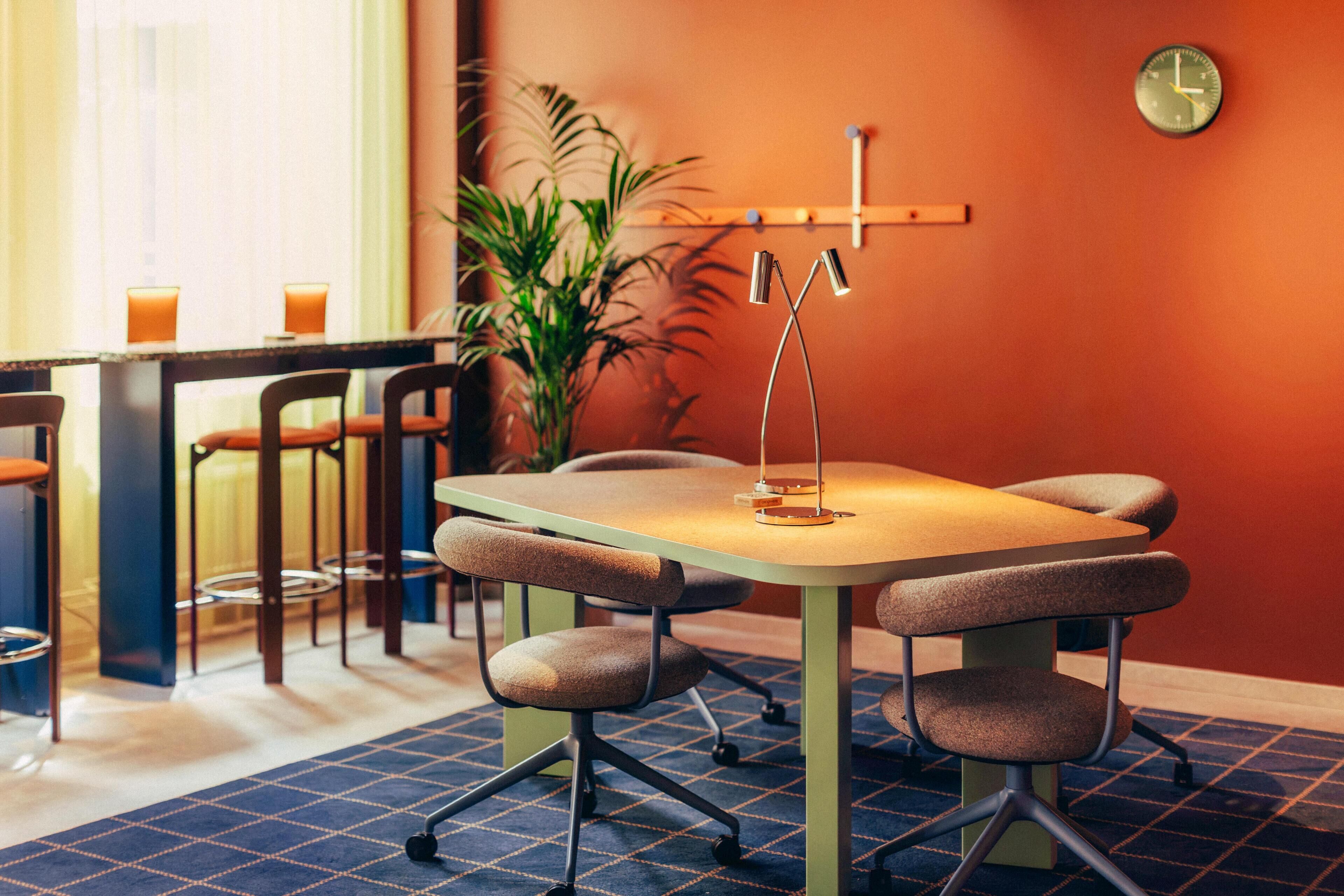 A conference room with a table, chairs, a clock, and a potted plant.