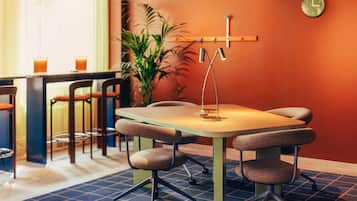 A conference room with a table, chairs, a clock, and a potted plant.