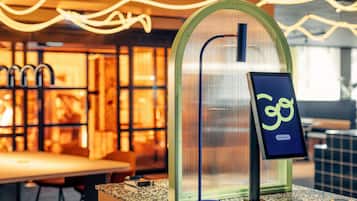 A modern interior with a glass partition, a digital sign, and a seating area.