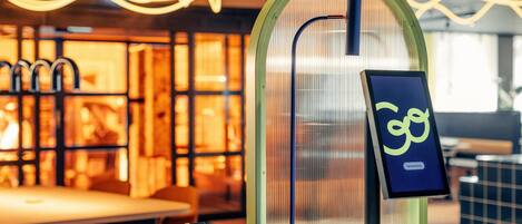 A modern interior with a glass partition, a digital sign, and a seating area.
