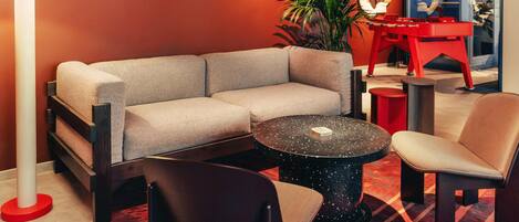 A modern lounge area with a sofa, chairs, a round table, a lamp, and a red cabinet.