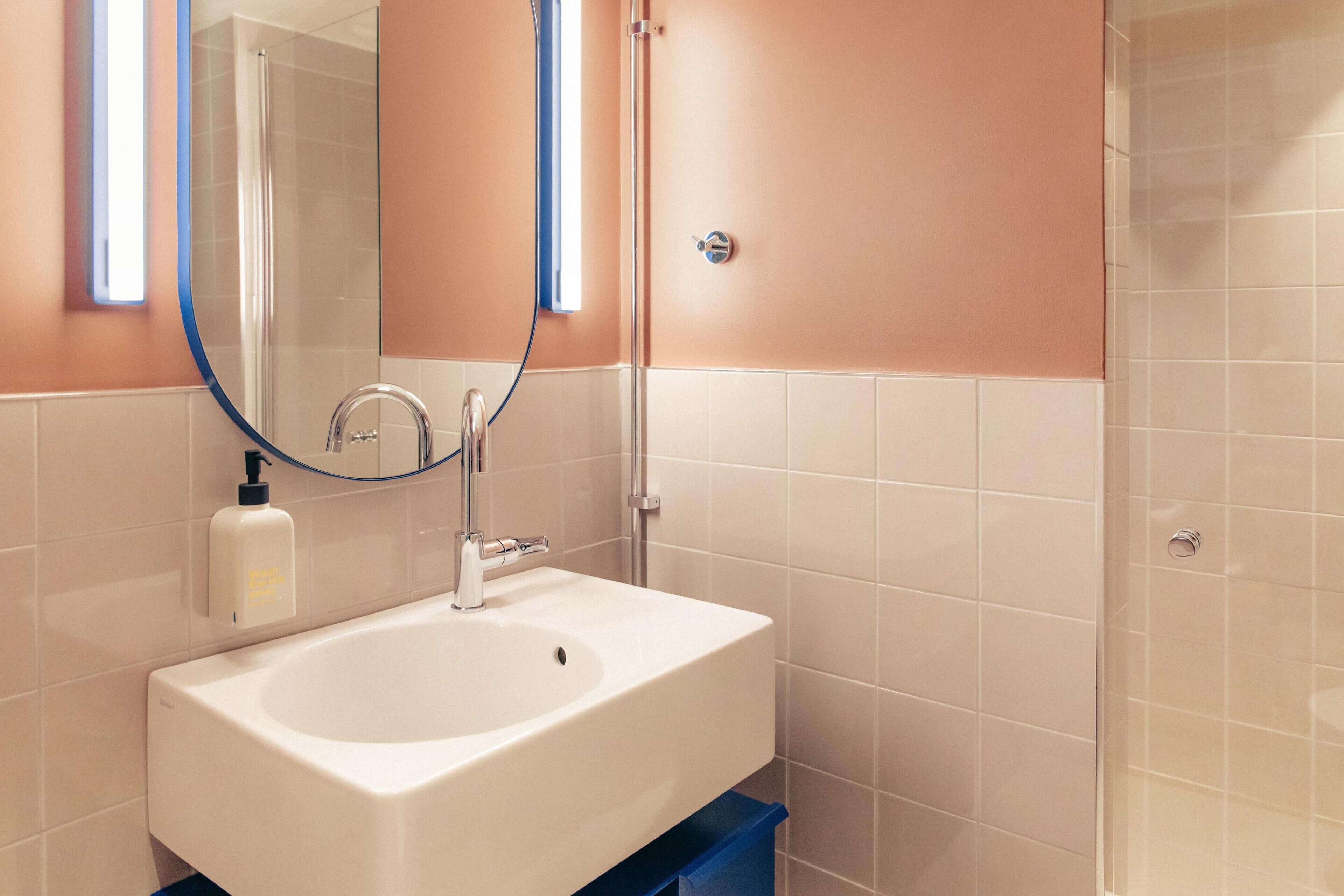 A bathroom with a white sink, a mirror, and a shower.