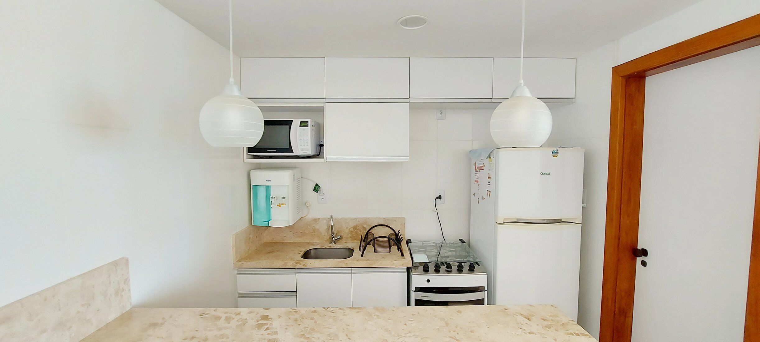 Una cocina compacta equipada con estufa a gas, microondas, refrigerador y pileta.
