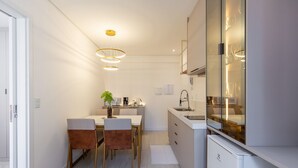 A modern kitchen with a dining area, featuring a white countertop, stainless steel appliances, and a pendant light fixture. - Apt w/ Amazing View in Curitiba Nfe0708 (Curitiba)