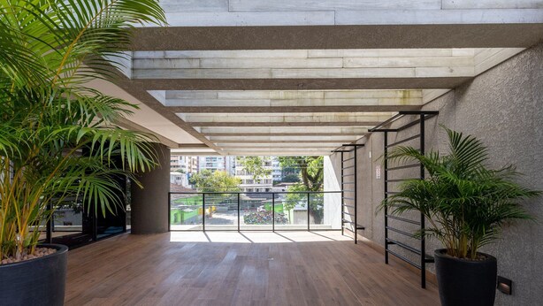 A spacious indoor area with a concrete ceiling, wooden flooring, and large potted plants. - Apt w/ Amazing View in Curitiba Nfe0708 (Curitiba)