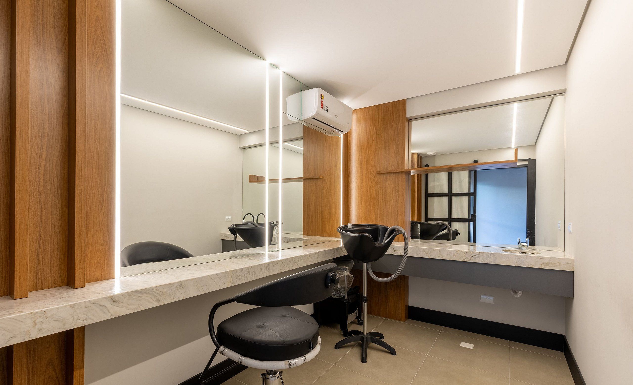 Un baño moderno con un espejo grande, una silla negra y una encimera.