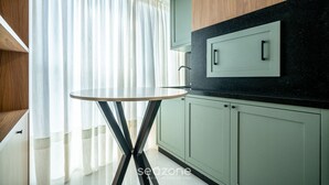 A modern kitchen with light green cabinets, a black countertop, and a round table. - Modern apt W/sea View in Porto Belo SC Mre801 (Porto Belo)