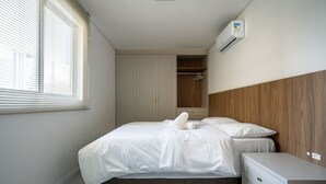 A bedroom with a bed, a bedside table, a wardrobe, and an air conditioning unit. - Modern apt W/sea View in Porto Belo SC Mre801 (Porto Belo)