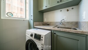 A laundry room with a washing machine, a sink, and cabinets. - Modern apt W/sea View in Porto Belo SC Mre801 (Porto Belo)