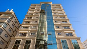 Un edificio de gran altura con fachada central de vidrio, múltiples balcones y un diseño arquitectónico moderno.