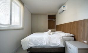 Una camera da letto con un letto, un comodino, un armadio e un condizionatore d'aria.