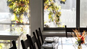 Une table à manger avec des chaises, un vase rempli de fleurs et une vue par la fenêtre.