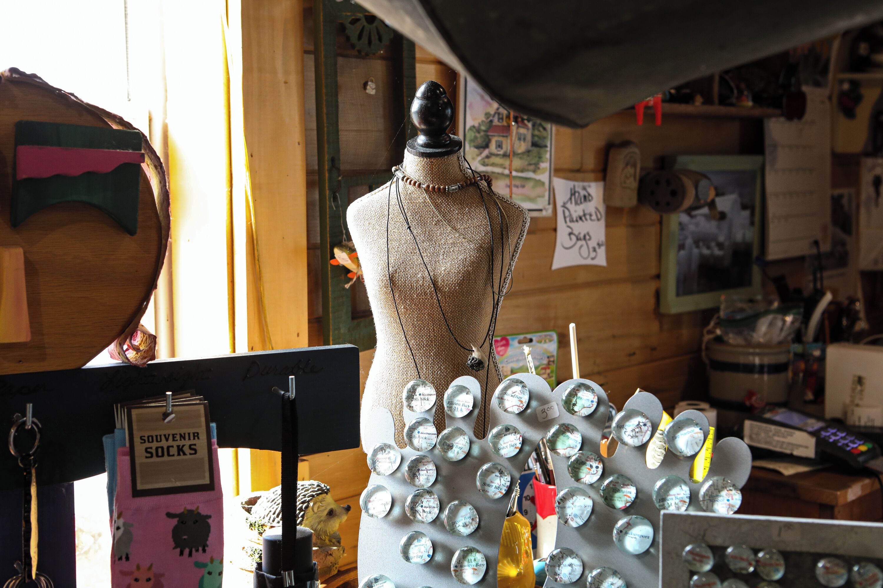 A mannequin in a shop with a display of bottle caps and a sign for 'souvenir socks'.