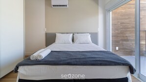 A modern bedroom with a large bed, a grey blanket, and a white duvet. - Penthouse 3 min From Jurere Beach - Mor0402 (Florianópolis)