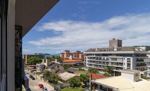 A residential area with multi-story buildings, a street with parked cars, and a clear sky. - Penthouse 3 min From Jurere Beach - Mor0402 (Florianópolis)