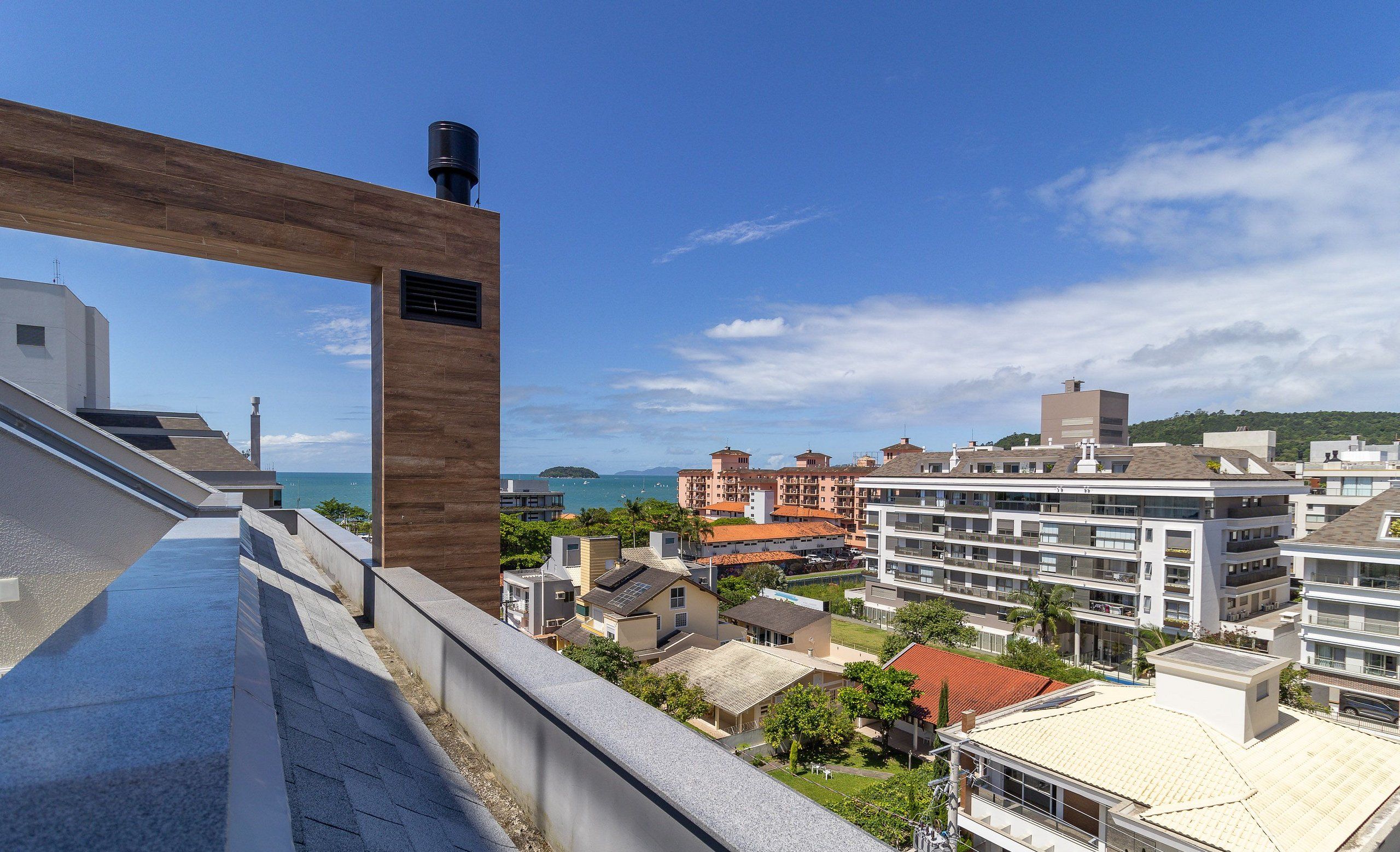 Un edificio moderno con facciata in legno e vista sul mare e su altri edifici.