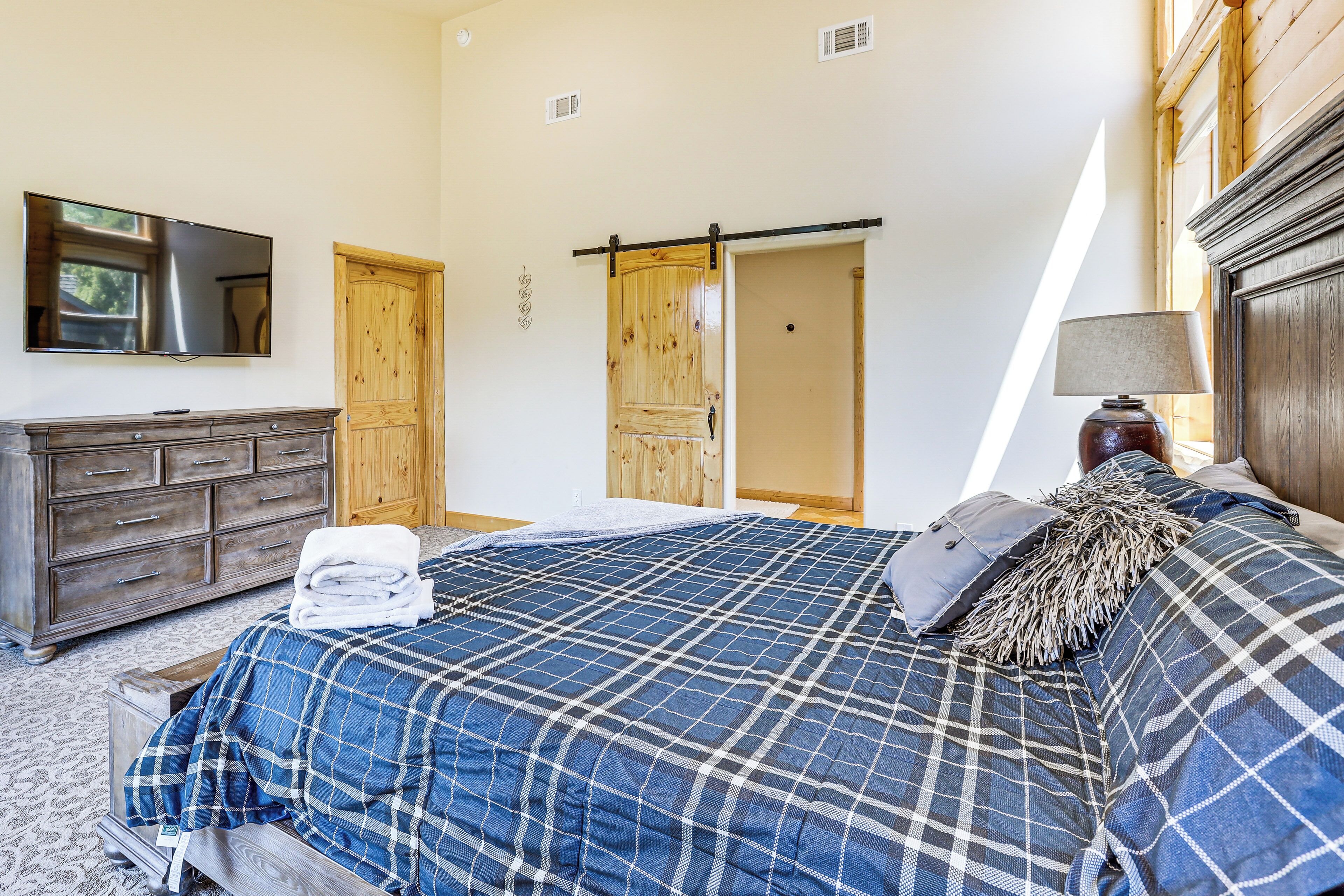 A bedroom with a bed, a dresser, a TV, and a door.