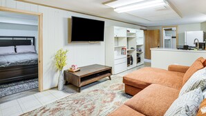 Uma sala de estar moderna com um sofá, uma televisão, uma mesa de centro e uma cama.