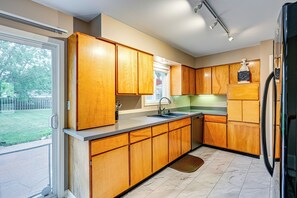 A kitchen with wooden cabinets, a sink, and a refrigerator. - 1 Mi to Dtwn: Suburban Home w/ Yard in Owosso (Owosso)