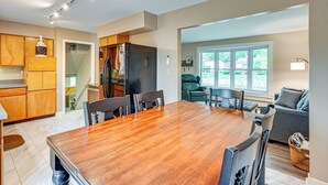 A spacious kitchen with wooden cabinets, a large wooden dining table, and a built-in refrigerator. - 1 Mi to Dtwn: Suburban Home w/ Yard in Owosso (Owosso)