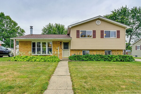 A two-story house with a front porch, a chimney, and a well-maintained lawn. - 1 Mi to Dtwn: Suburban Home w/ Yard in Owosso (Owosso)