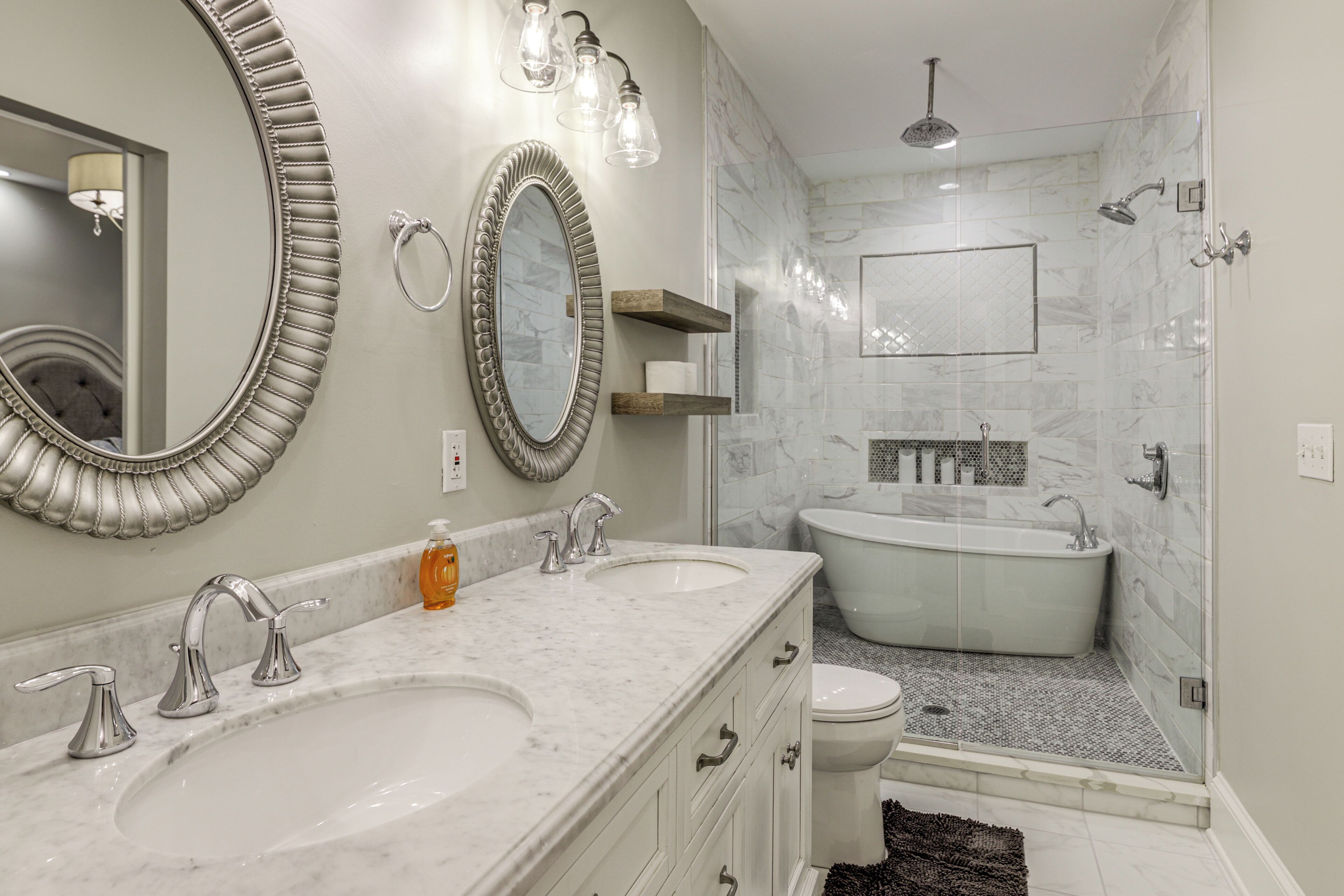 Une salle de bain avec deux lavabos, un grand miroir et une baignoire sur pieds.