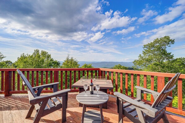 Une terrasse en bois avec une table et deux chaises, une bouteille et deux verres.